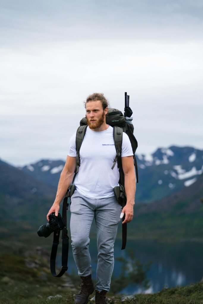 Photographer hiking in Norwegian mountains carrying a camera, showcasing rugged nature and adventure.