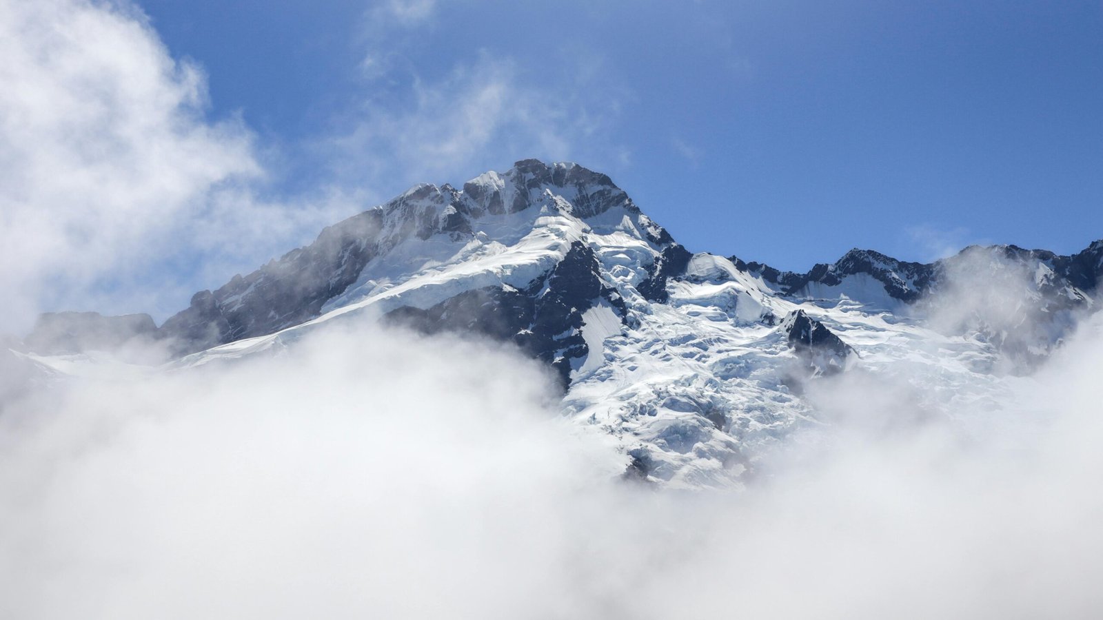 Stunning view of the snow-covered mountain peaks surrounded by clouds.