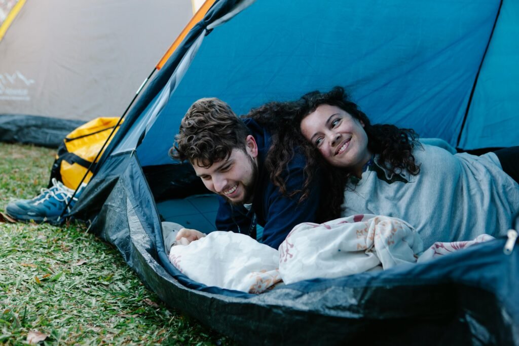 A cheerful couple relaxing inside a tent during a camping trip, enjoying nature and each other's company.